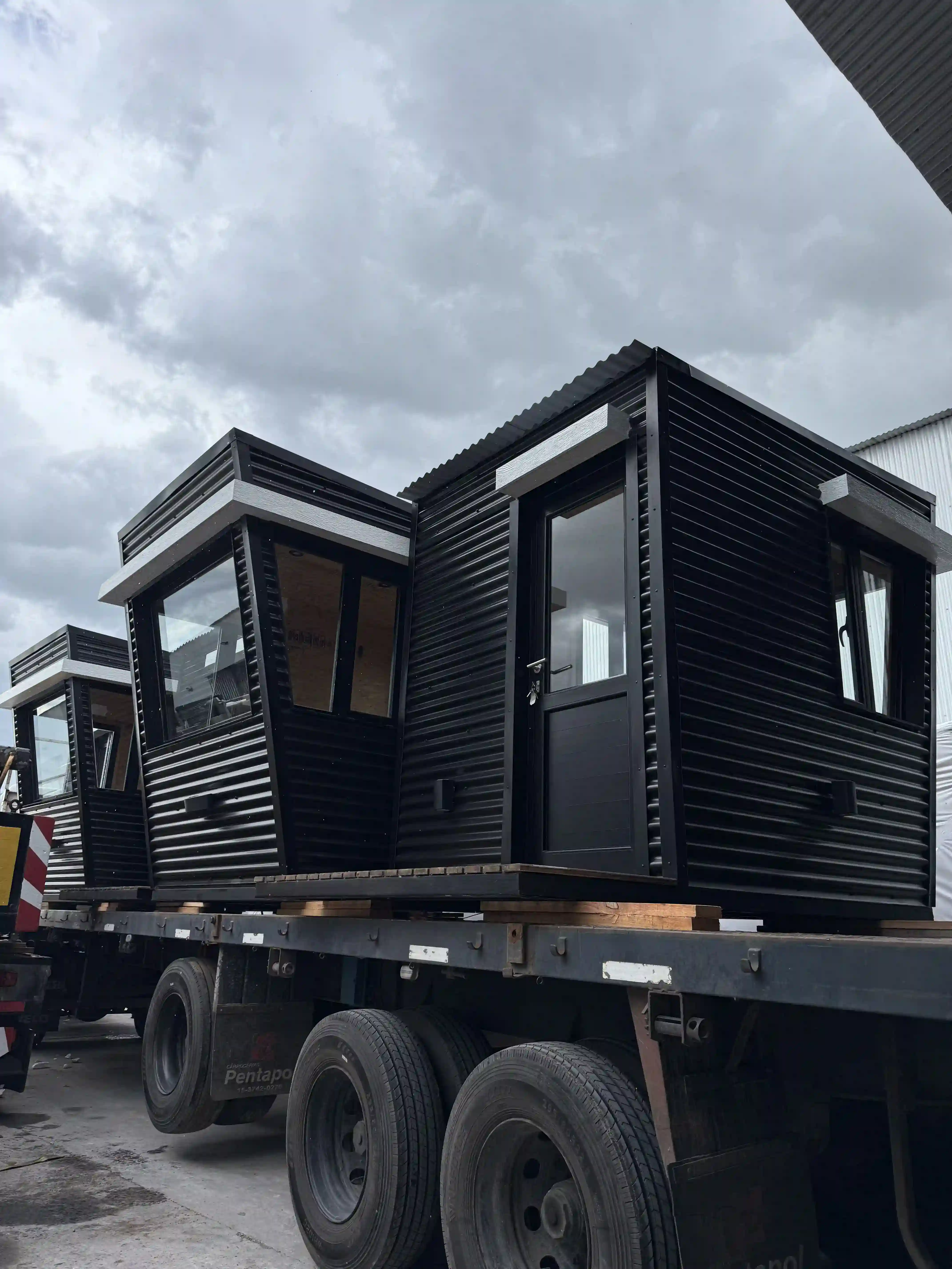Módulos modulares negros sobre camión listos para entrega Faci House