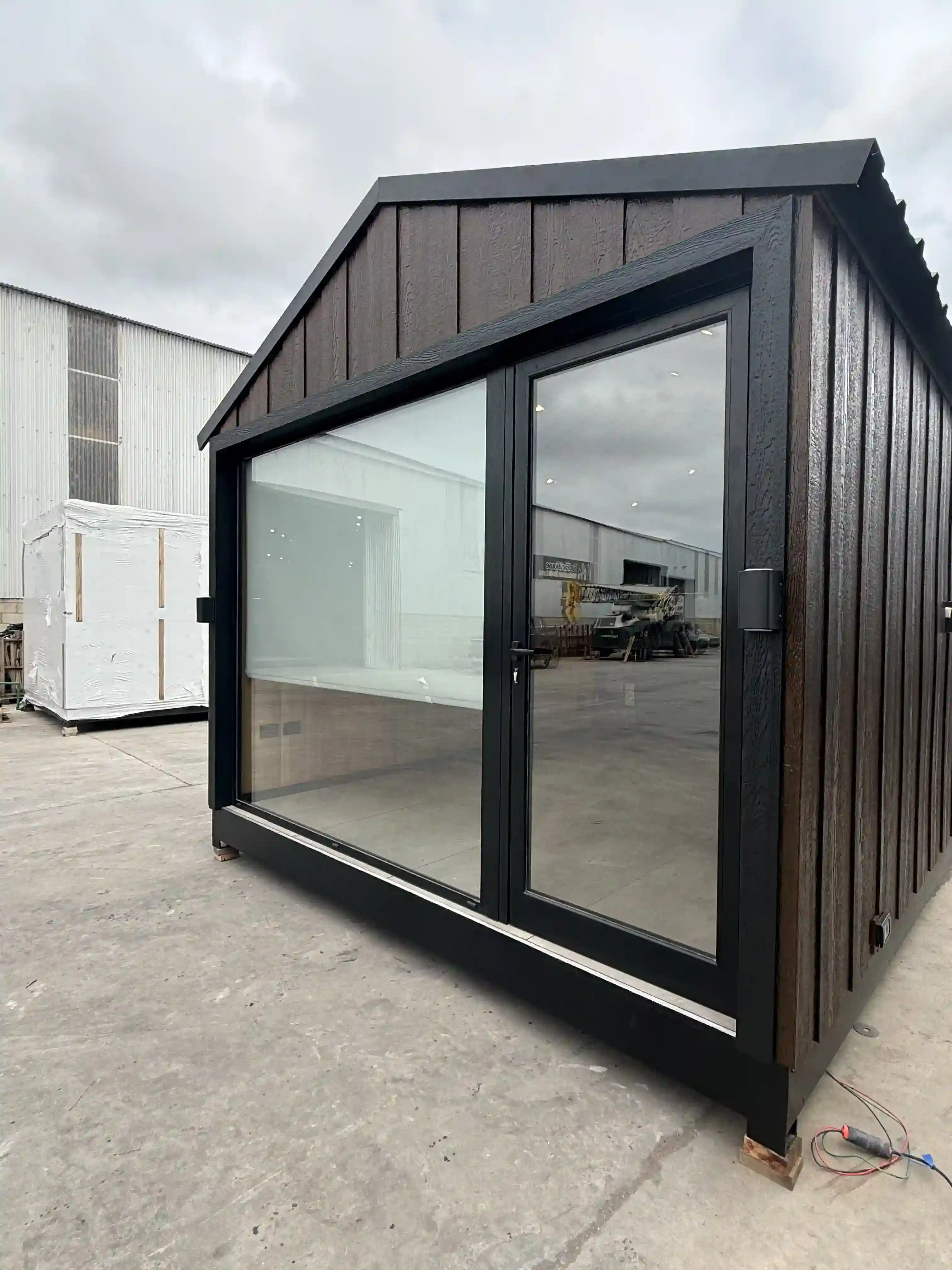 Módulo con frente vidriado y revestimiento de madera oscura Faci House