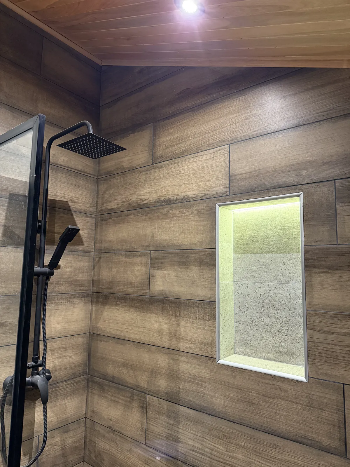 Ducha tipo lluvia con nicho iluminado y porcelanato símil madera casa modular Faci House