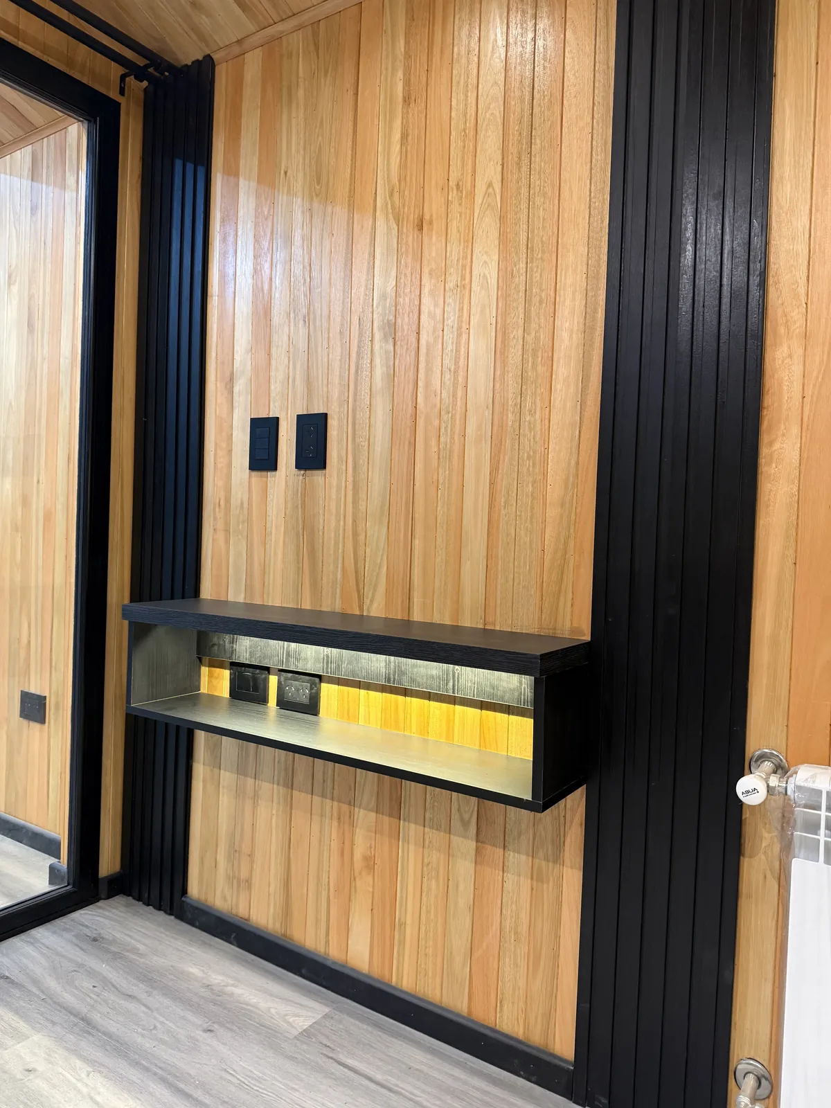 Detalle de repisa flotante con luz LED y listones negros casa modular Faci House