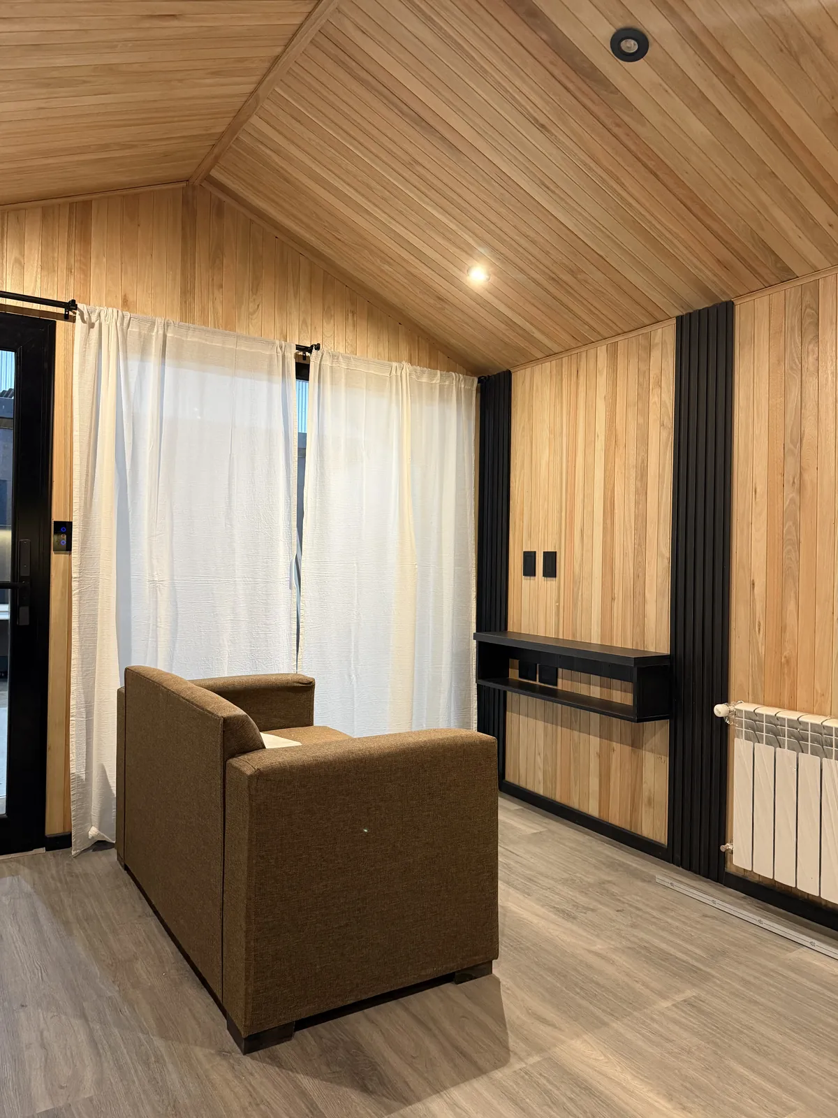 Living con sillón, ventanal y revestimiento de madera casa modular Faci House