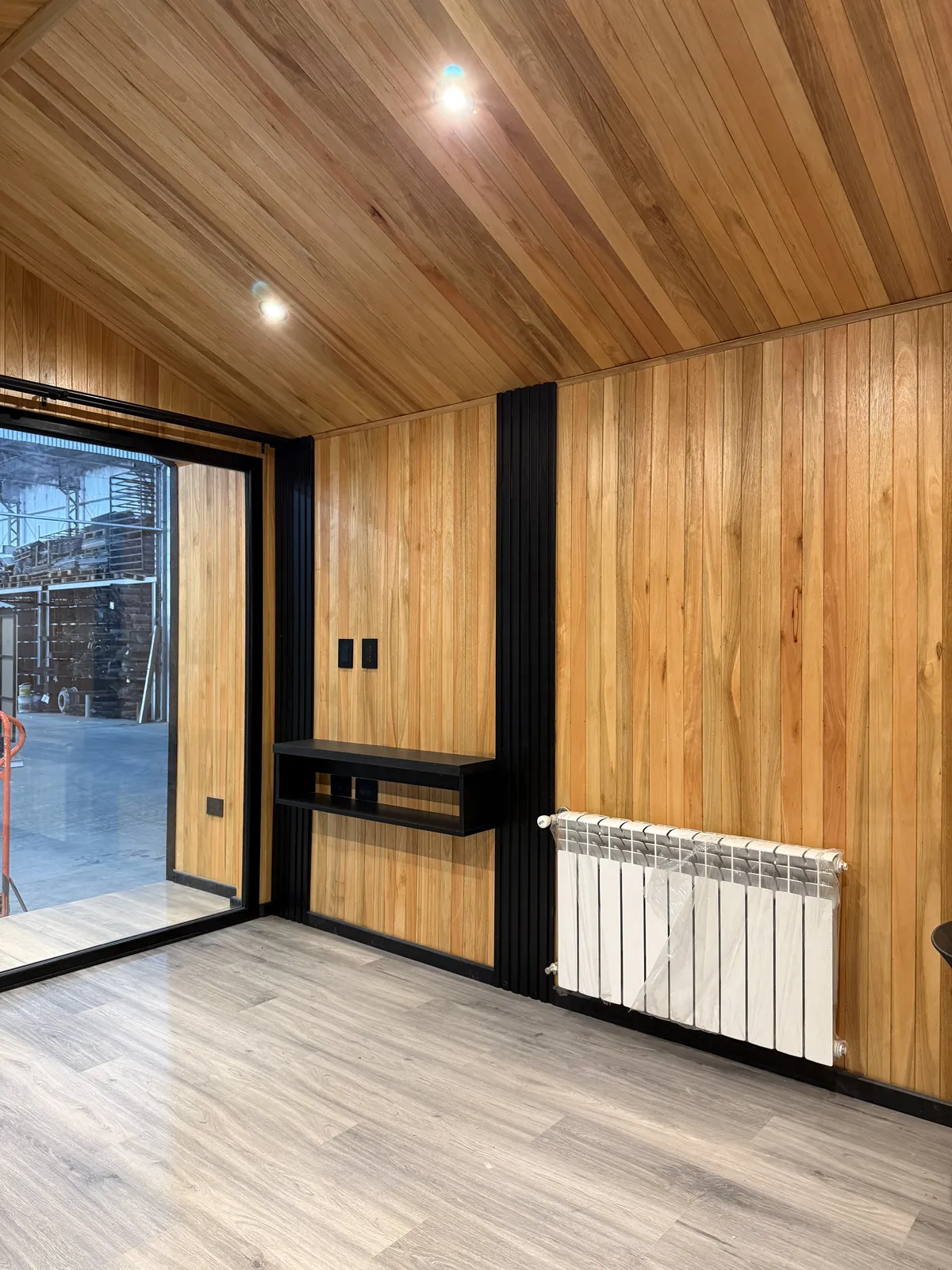Living luminoso con puerta ventana corrediza y revestimiento de madera casa modular Faci House