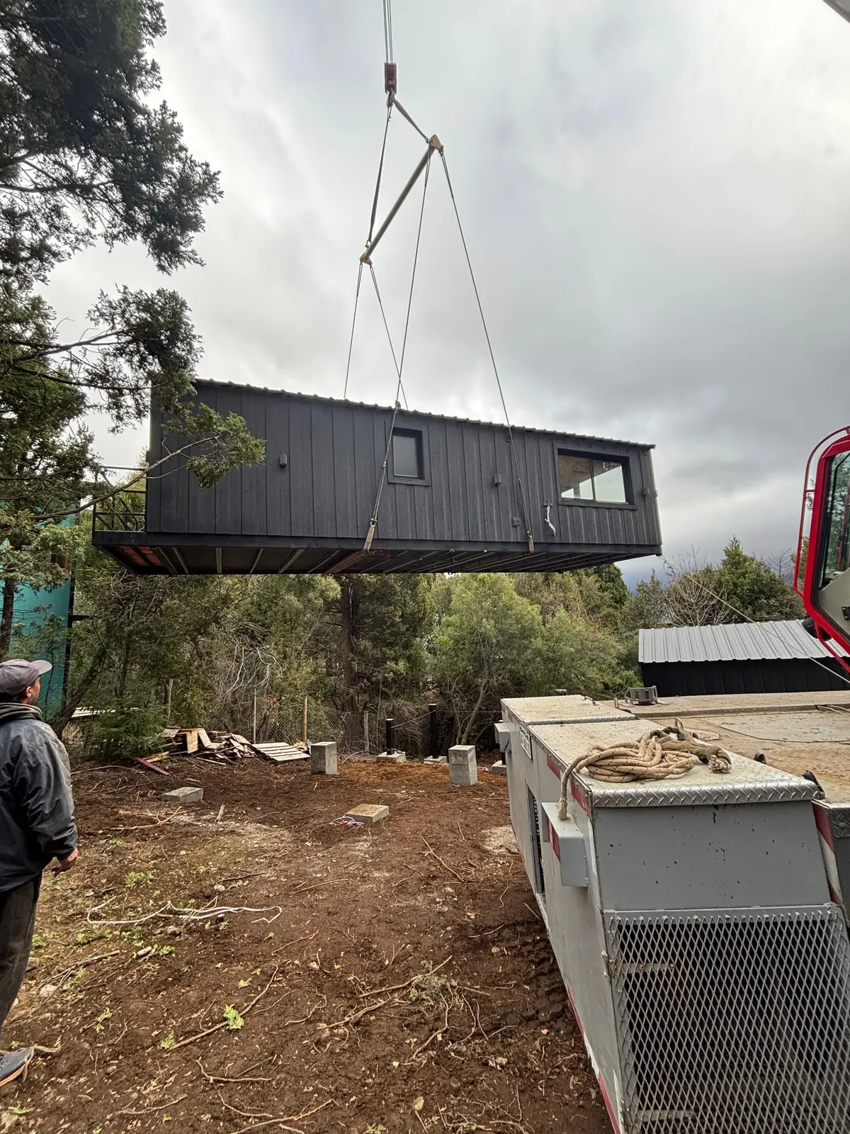 Izaje de módulo negro con grúa entre los árboles Faci House